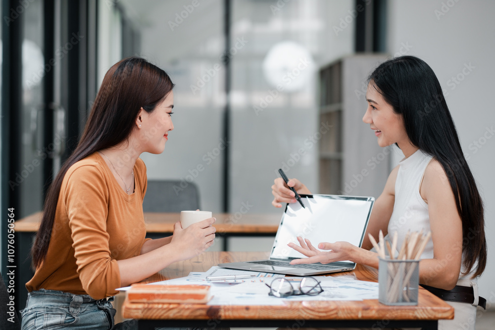 Two women discussing business strategies in a modern office setting, showcasing teamwork and collaboration. Two women discussing business strategies in a modern office setting, showcasing teamwork and collaboration.