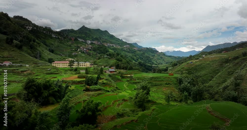 Drone establishing dolly over Sapa Valley terraced agricultural landscape with large buildings and farm houses along hillside Drone establishing dolly over Sapa Valley terraced agricultural landscape with large buildings and farm houses along hillside