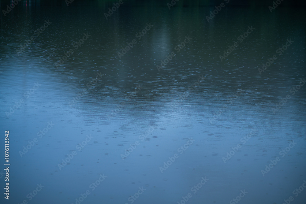 Fototapeta premium ฺBeautiful Reflected the Rain falls on the water surface in nature forest Mountain natural atmosphere rain fog sky abstract with white clouds background.