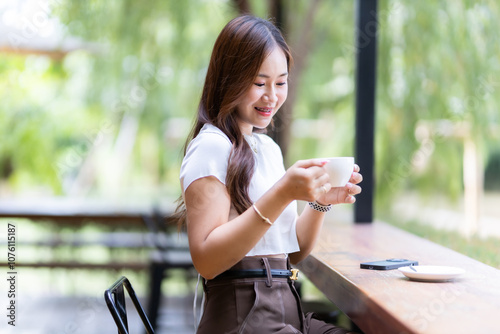 Portrait of beautiful happy Smiling Holding a glass of Hot coffee latte asian woman relaxing sitting and smartphone in cafe interior in coffee shop background,Business Lifestyle summer holiday concept