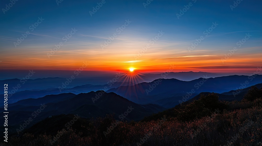 Fototapeta premium Stunning sunset in the mountains, creating a breathtaking blend of orange and blue skies. Perfect for capturing the serene beauty of sunsets in the mountains with ample copy space.