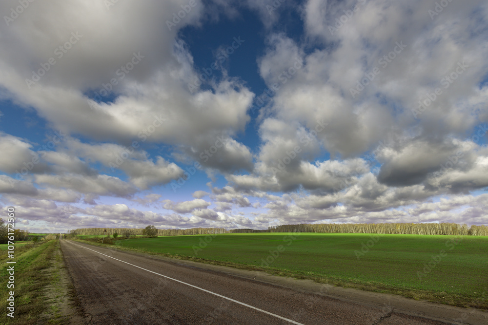 A road with a few trees in the background and a cloudy sky A road with a few trees in the background and a cloudy sky