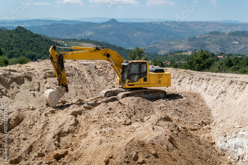 Escavadeira de esteiras a trabalhar na construção de uma barragem para armazenamento de água para rega agrícola photo