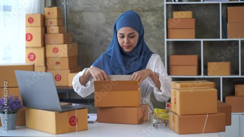 Entrepreneurial Woman Packing Order: A focused Muslim woman in a hijab carefully packs an order amidst a stack of shipping boxes, showcasing dedication and the dynamism of online business.  