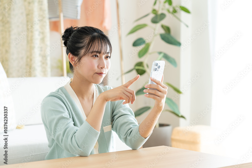 リビングでスマホを見る若い女性 リビングでスマホを見る若い女性