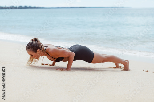 Woman doing push up on white sand beach photo