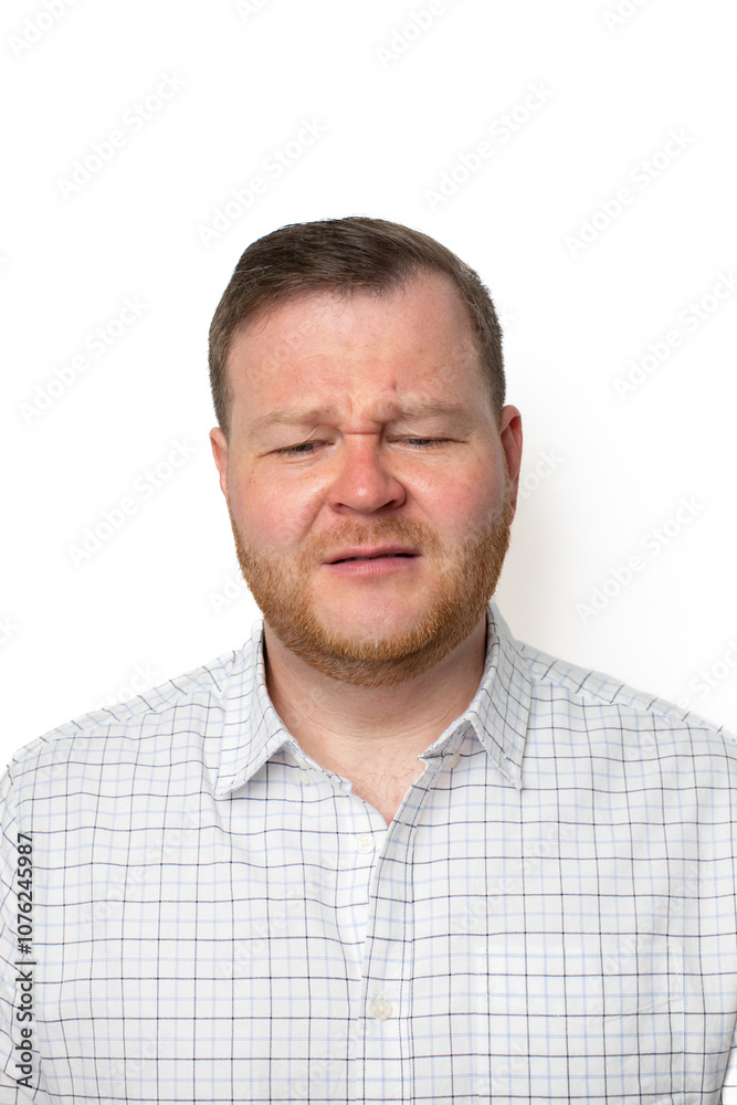 A Caucasian man in a checked shirt squints uncomfortably at the camera, illustrating the concept of eye strain A Caucasian man in a checked shirt squints uncomfortably at the camera, illustrating the concept of eye strain