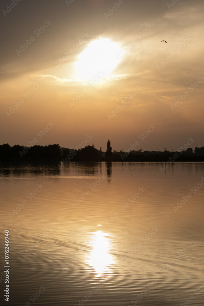 Fototapeta premium Serene sunset over a tranquil lake reflecting golden hues, symbolizing peace and introspection, perfect for relaxation themes