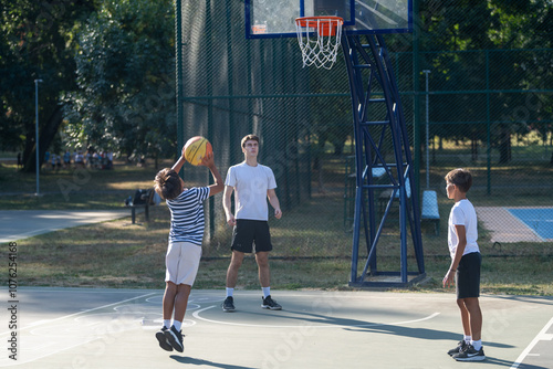 Boys participate in outdoor basketball training with a coach, focusing on teamwork, skills development, and building athletic confidence in a supportive sports environment