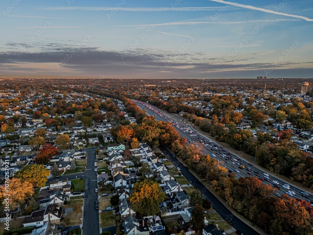Fototapeta premium Aerial view of suburb with autumn colors and highway traffic.