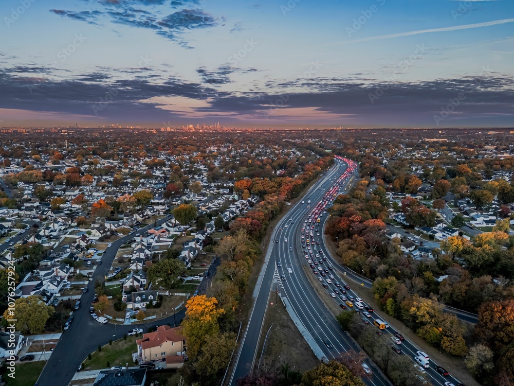 Fototapeta premium Suburban sunset with highway and city skyline.