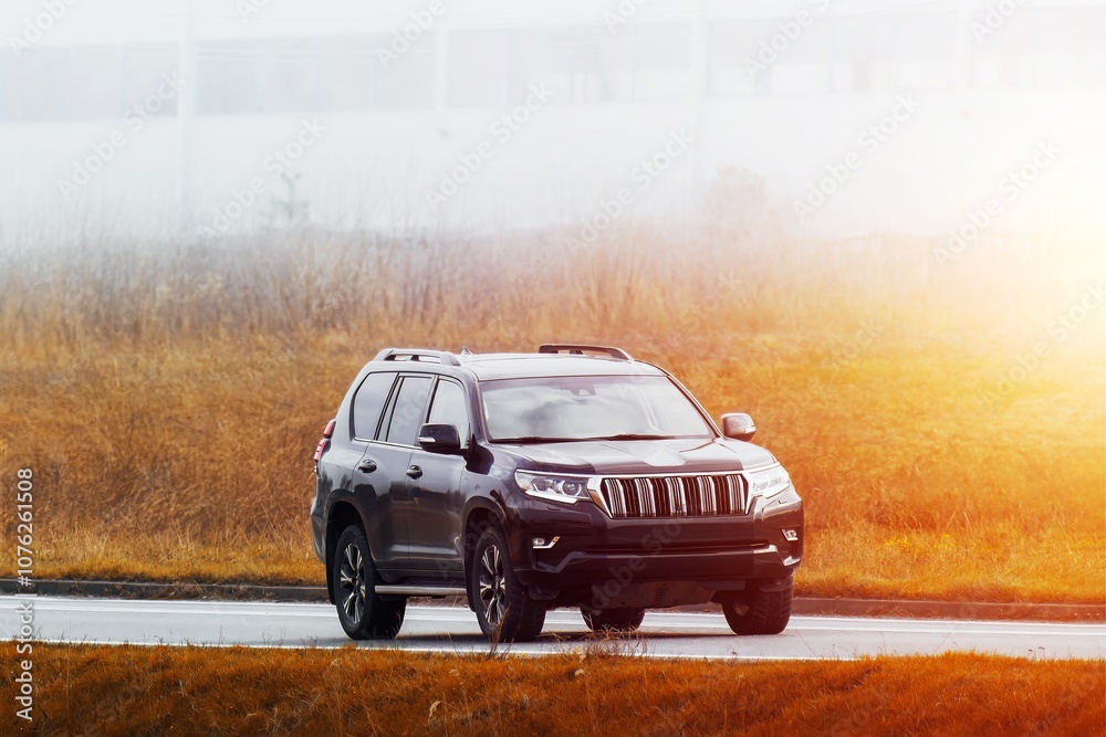 Fototapeta premium Elegant black SUV driving through scenic green countryside