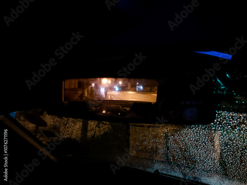 car rear view at night during raining and the silhoute of a girl walking on the street photo