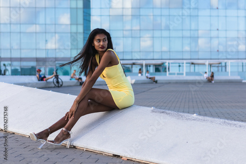 Fashion model posing in a yellow dress in front of the barcelona international convention centre photo