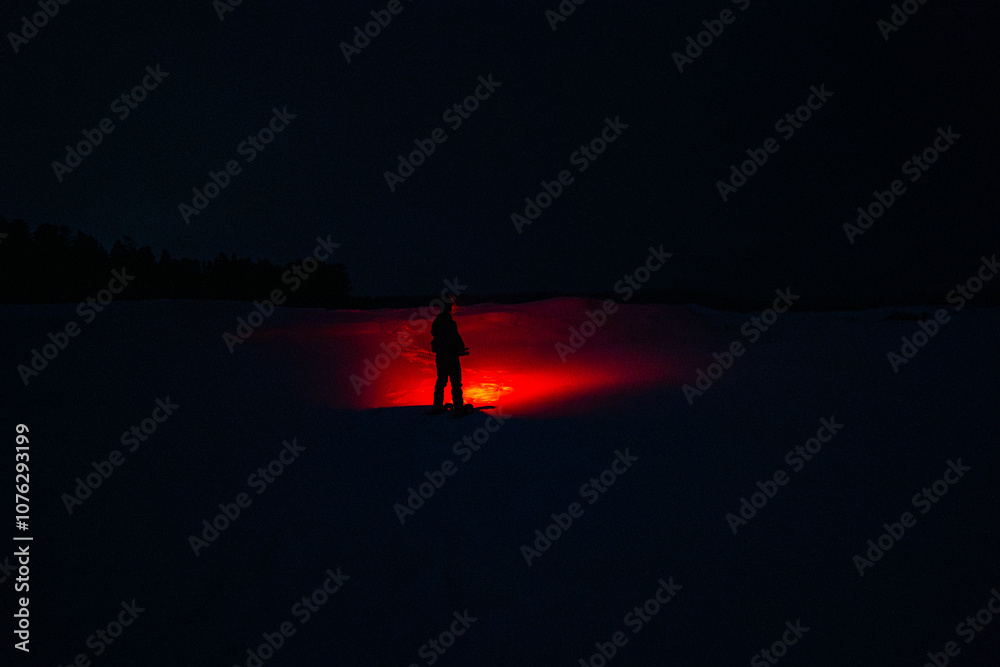 A Person in the Snow Shining a Creepy Red Flashlight in the Dark Night