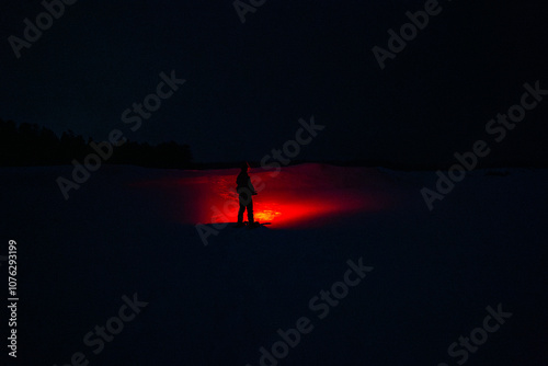 A Person in the Snow Shining a Creepy Red Flashlight in the Dark Night