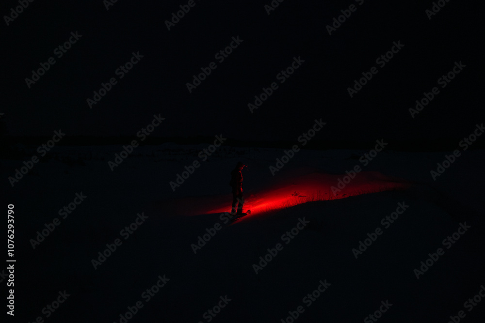 A Person in the Snow Shining a Creepy Red Flashlight in the Dark Night