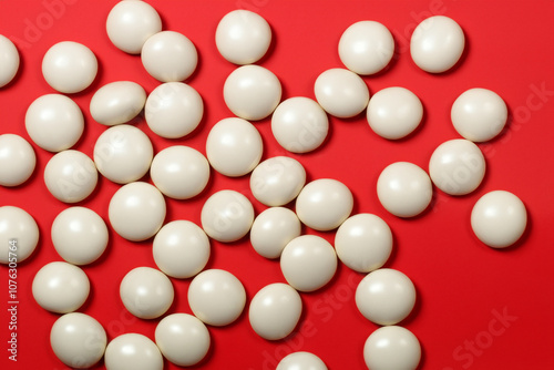 Small round lying on white and red with candies. lie jar concept. a small round candies lying on a white and red with candies. a small round candies with a sweet treat on the side lifestyle.