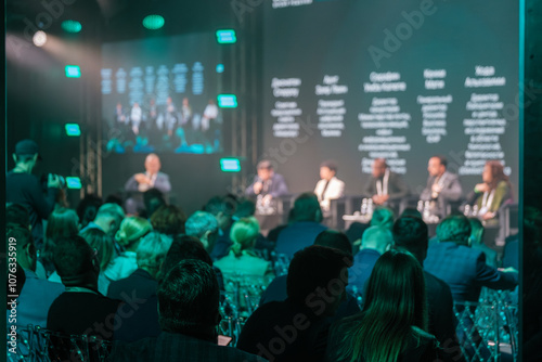 Audience attending business conference featuring diverse panelists discussing key industry topics in modern setting.
