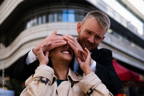 Businessman covering eyes of businesswoman in front of building photo