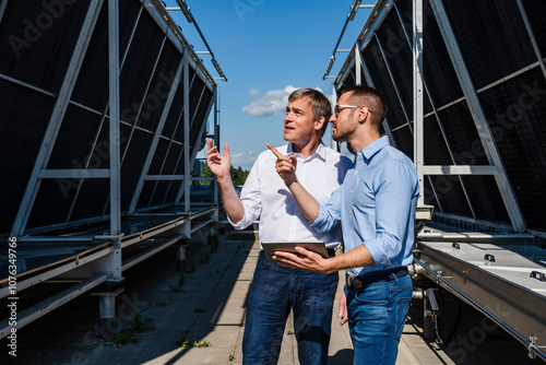 Two businessmen discussing on rooftop beside refrigeration installation photo