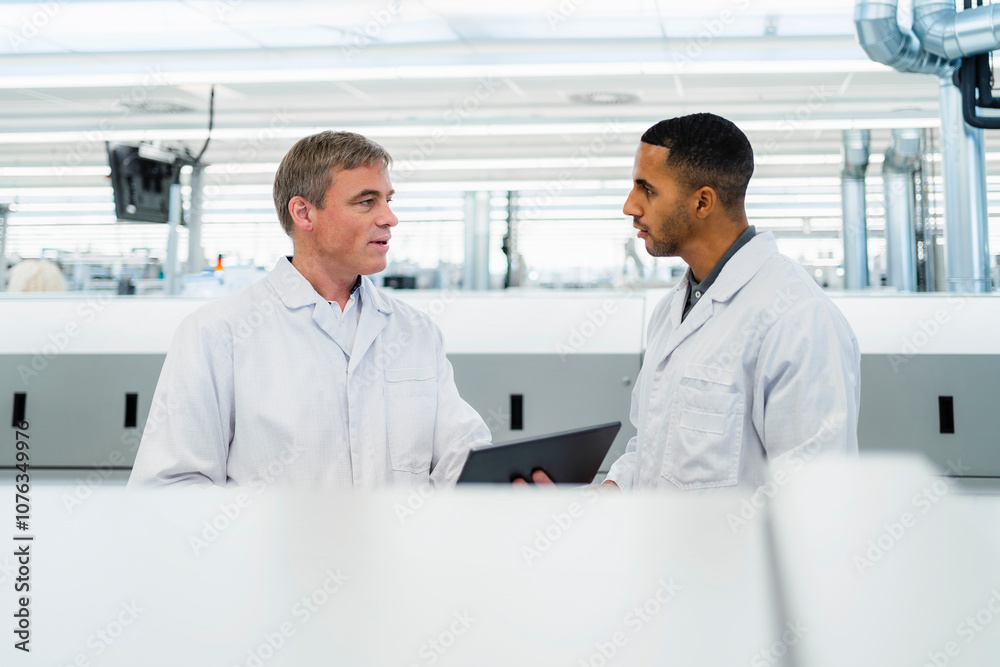 Team of competent electrical technicians in lab coats having meeting in electronics factory Team of competent electrical technicians in lab coats having meeting in electronics factory