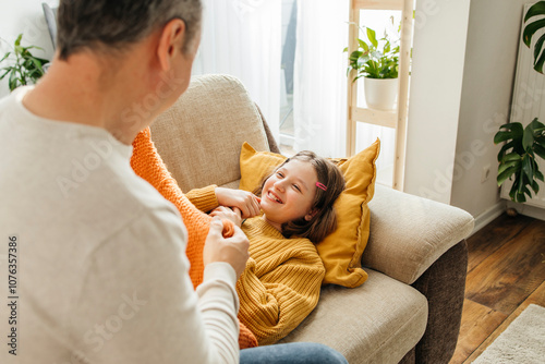 Father taking care of daughter resting on sofa at home