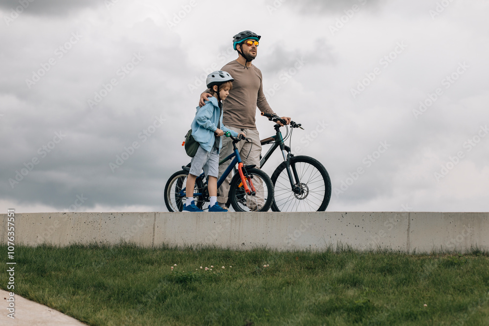Father and son with bicycles walking together on footpath Father and son with bicycles walking together on footpath