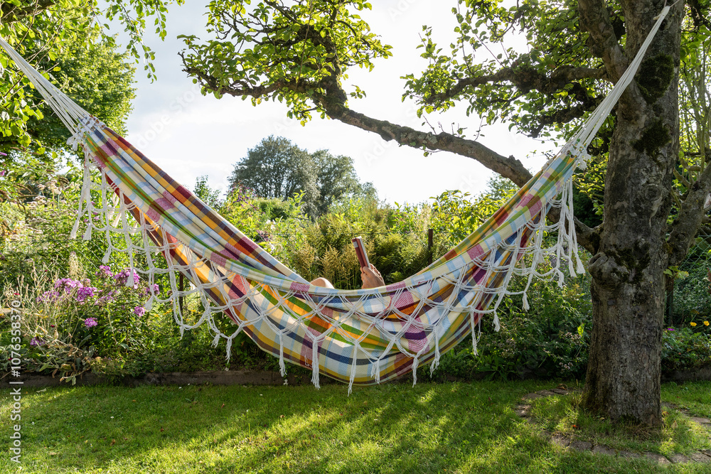 Senior man reading book and resting in hammock at garden Senior man reading book and resting in hammock at garden