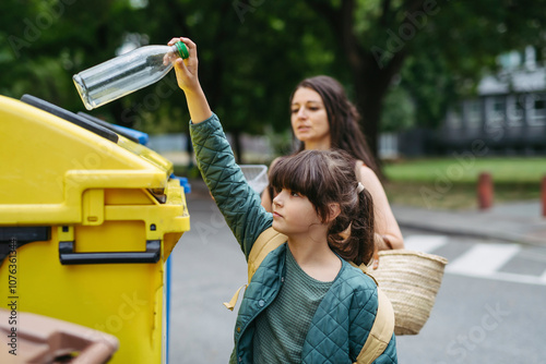 Mother and schoolgirl daughter separate waste into recycling bins in the city photo