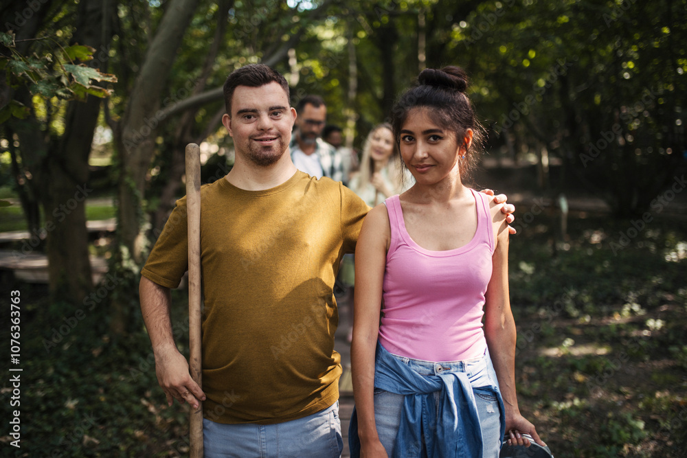 Young man with down syndrome taking part in community cleanup with his female friend Young man with down syndrome taking part in community cleanup with his female friend