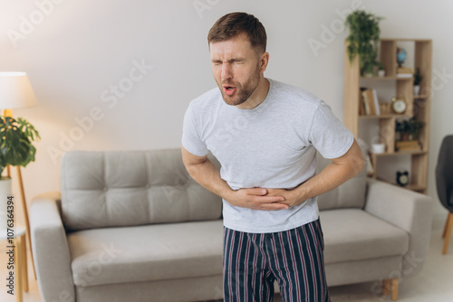 Stomach ache, man with abdominal pain suffering at home, health problems concept photo