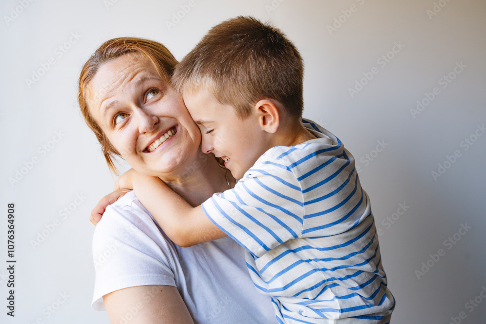 Happy boy embracing mother in front of wall at home Happy boy embracing mother in front of wall at home