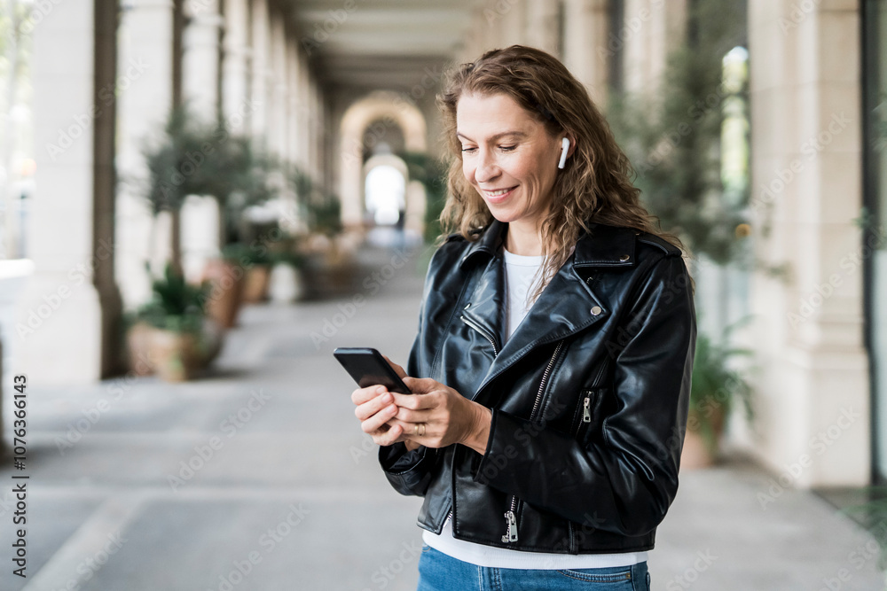 Smiling woman in leather jacket using smart phone Smiling woman in leather jacket using smart phone