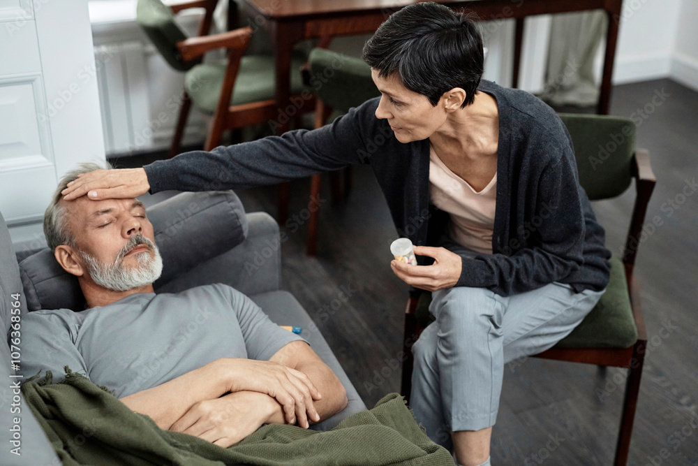 Woman touching forehead of sick husband and holding pills Woman touching forehead of sick husband and holding pills