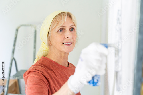 Senior woman painting wall at home photo