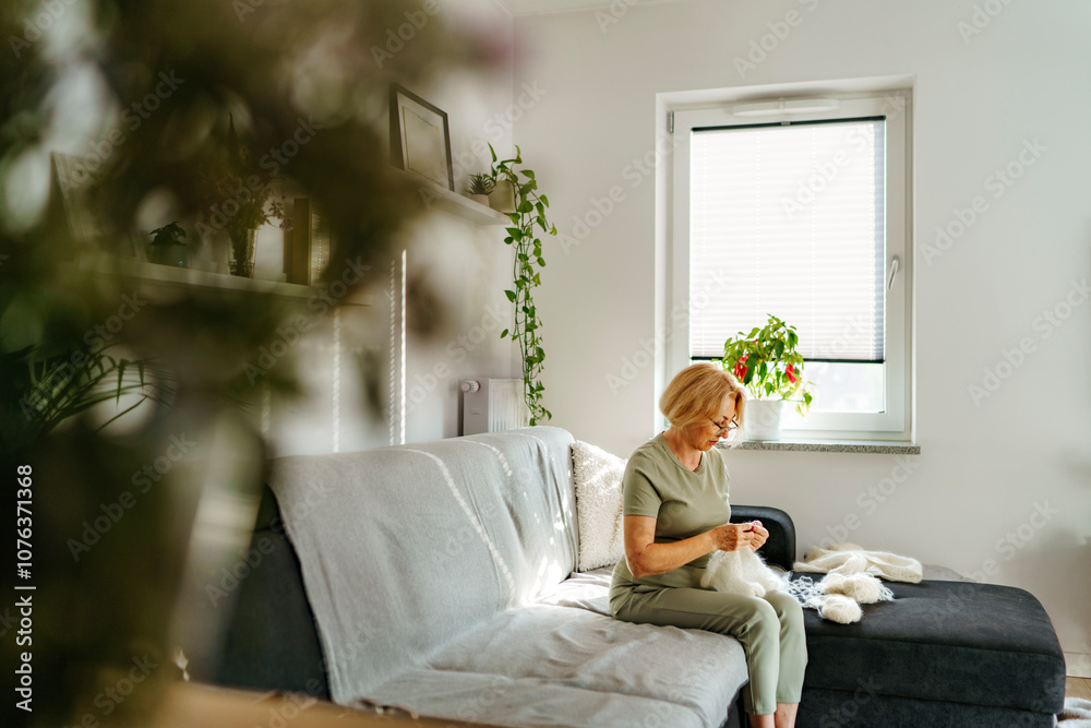 Senior woman knitting and sitting on sofa at home Senior woman knitting and sitting on sofa at home