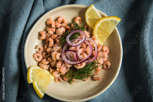 Norddeutsche Friesische Nordseekrabben  mit Zitrone, rote Zwiebel und Dill in Porzellan Schale auf hell blau Serviette und rustikal dunkel Holz Hintergrund