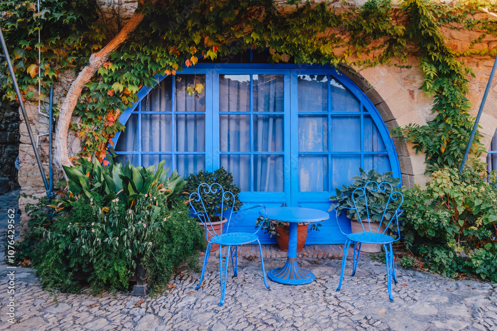 Charming Mediterranean Courtyard with Blue Vintage Furniture and Climbing Plants. Hidden Gem in Medieval Peratallada, Costa Brava, Spain (Peratallada, Catalonia)
