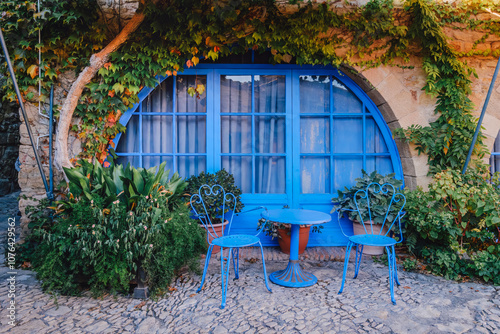 Obraz na płótnie Charming Mediterranean Courtyard with Blue Vintage Furniture and Climbing Plants. Hidden Gem in Medieval Peratallada, Costa Brava, Spain (Peratallada, Catalonia) w salonie