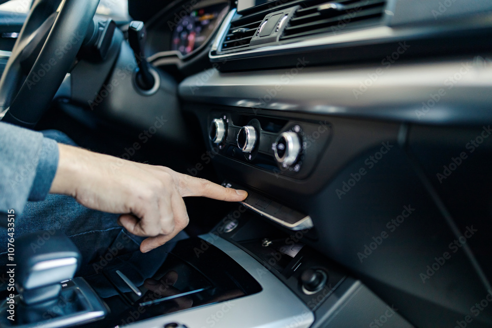Close up of a hand turning on air conditioner in a car.