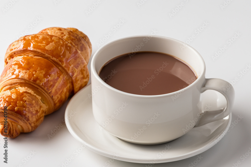 Croissant with chocolate and white icing on . food dessert sweet concept. w standing on white with mug of coffee and croissant. a w stands on a white with a mug of coffee and a lifestyle croissant.