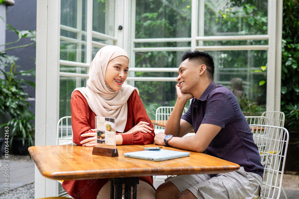 A joyful couple sharing laughter and bonding at an outdoor cafe table, surrounded by lush greenery and cozy atmosphere. Perfect representation of happiness and connection. A joyful couple sharing laughter and bonding at an outdoor cafe table, surrounded by lush greenery and cozy atmosphere. Perfect representation of happiness and connection.