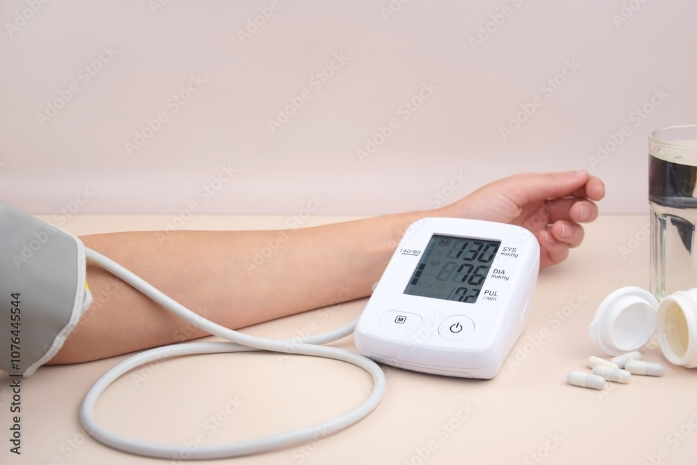 Digital blood pressure tonometer and pack of pills on a light background with copy space. Digital blood pressure tonometer and pack of pills on a light background with copy space.