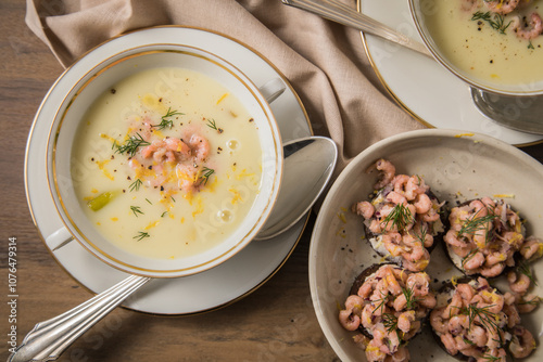 Ostfriesische Greetsieler Krabbensuppe mit Canapés, Nordseekrabben, Dill, Kartoffel, Lauch und Zitrone in Suppentasse mit Silberlöffel auf Holztisch und Tischdecke festlich