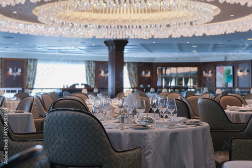 Formal and elegant ocean view dining room restaurant onboard luxury cruiseship or cruise ship liner with set tables in Country Club interior design style and ceiling ambient lighting
