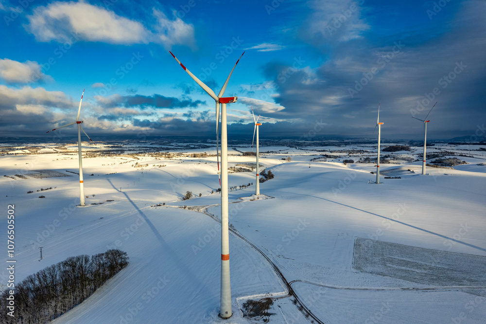 Drone shot of wind turbines in late afternoon light in flat snowy northern German landscape