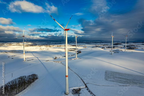 Obraz na płótnie Drone shot of wind turbines in late afternoon light in flat snowy northern German landscape w salonie