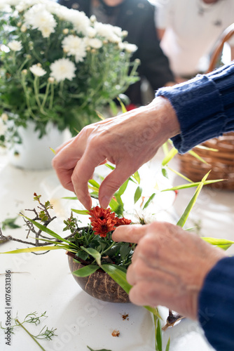 Obraz na płótnie Detail of hands decorating ikebana, Japanese floral decoration workshop, in the out-of-focus background more plants. w salonie