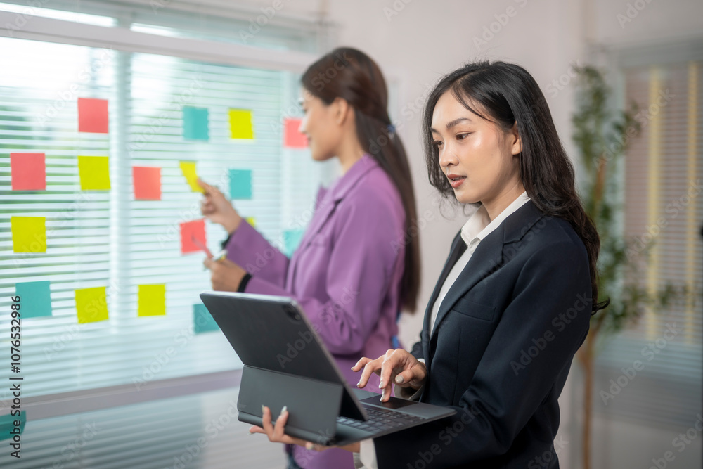 Two women in business suits are working on a project together Two women in business suits are working on a project together